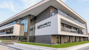 Un hotel moderno con techo plano, grandes ventanas de vidrio y un cartel que dice "Barati Boutique Hotel".