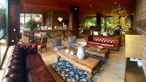 Een ruime lobby met leren banken, een houten salontafel en een grote vaas.