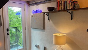 Une pièce confortable avec une porte donnant sur un balcon, une bibliothèque, une lampe et un fauteuil.