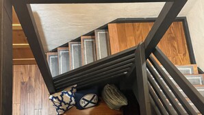 Un escalier avec une rampe en bois et une étagère ornée de coussins décoratifs et d’un tapis.
