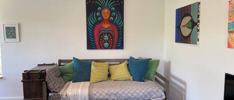 A cozy room with a wooden bed, colorful pillows, and a large abstract painting on the wall.
