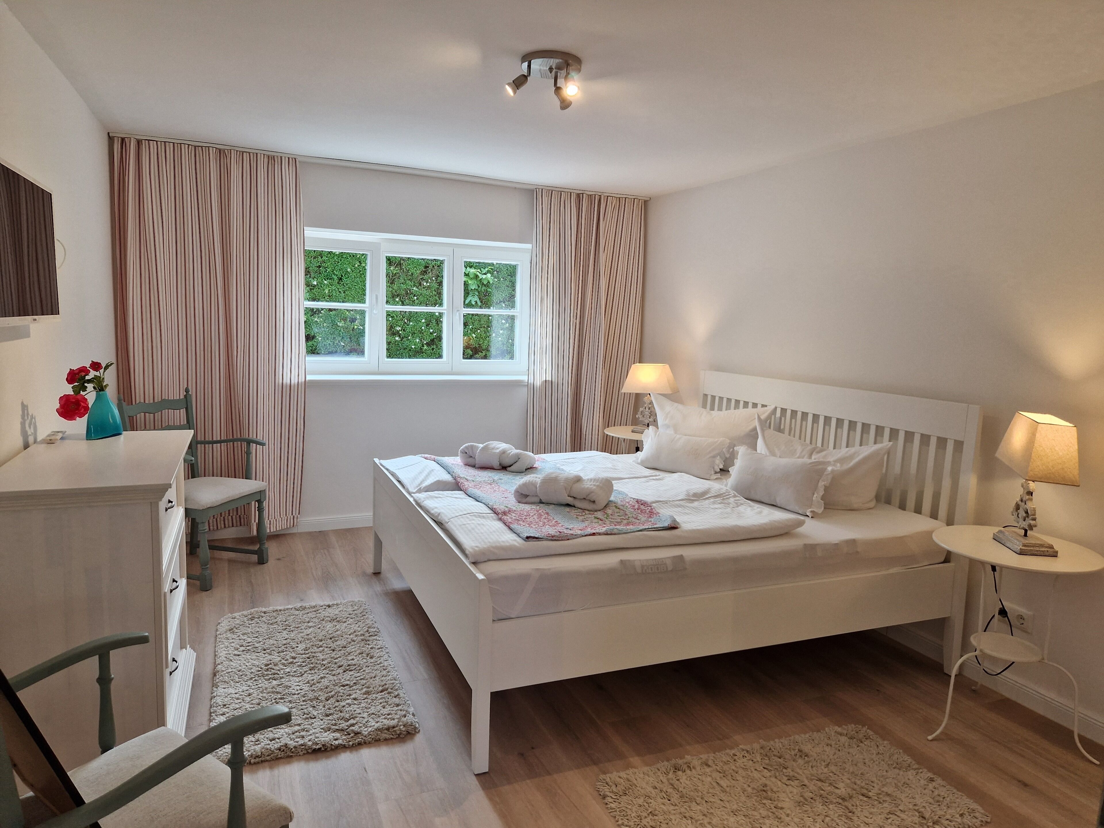 A bedroom with a bed, bedside tables, a desk, and a chair.