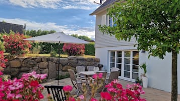 Een terras met tuinmeubilair, een stenen muur en een grote parasol.