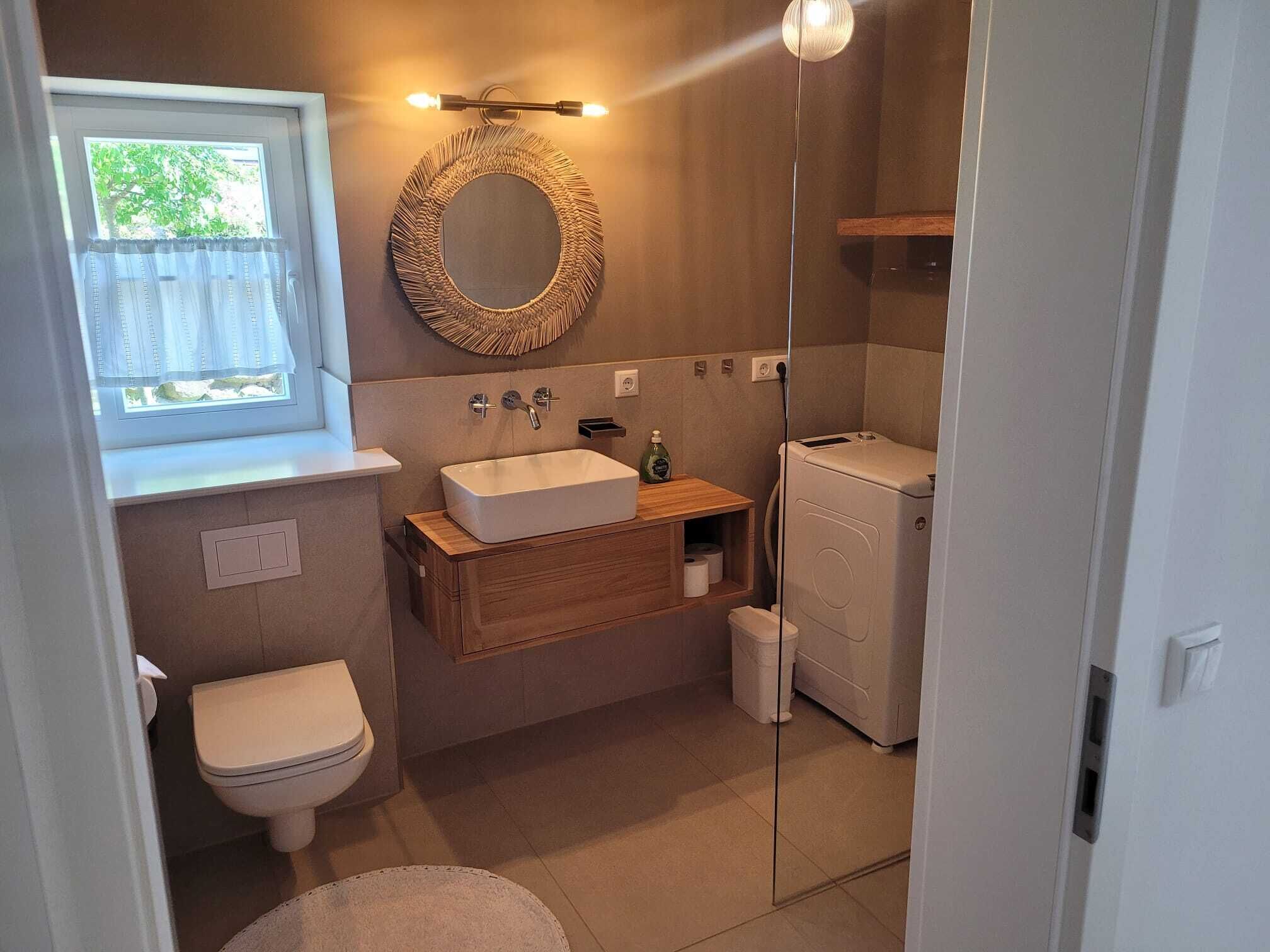 A compact bathroom with a toilet, sink, and washing machine.