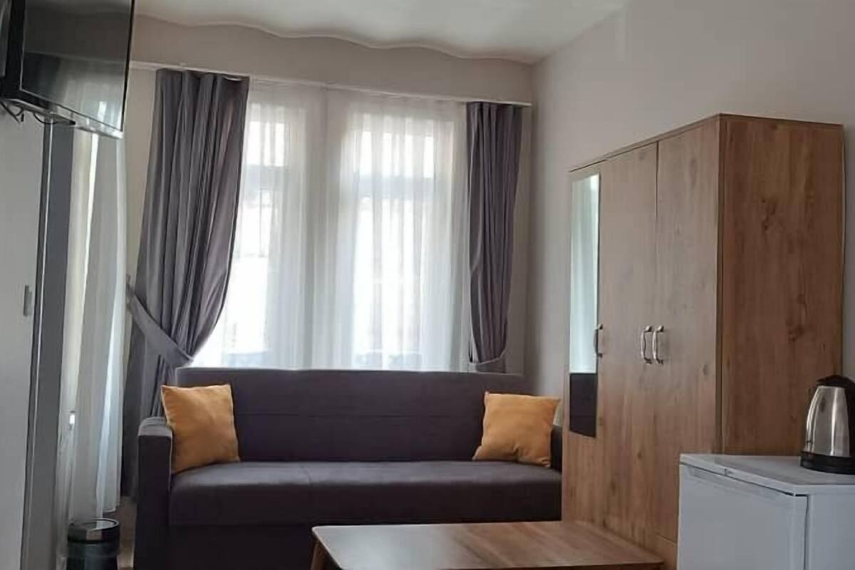 A room with a dark sofa, two cushions, a wooden cabinet, and a small table.