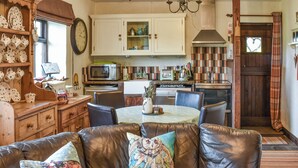 Ein gemütliches Wohnzimmer mit Ledersofa, Esstisch und Küchenbereich inklusive Schränke und Geräte.