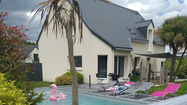 Uma piscina com espreguiçadeiras e um flutuador em formato de flamingo rosa.