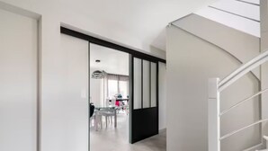 Interior moderno com uma escada, área de jantar com mesa e cadeiras, e vista para outro cômodo.