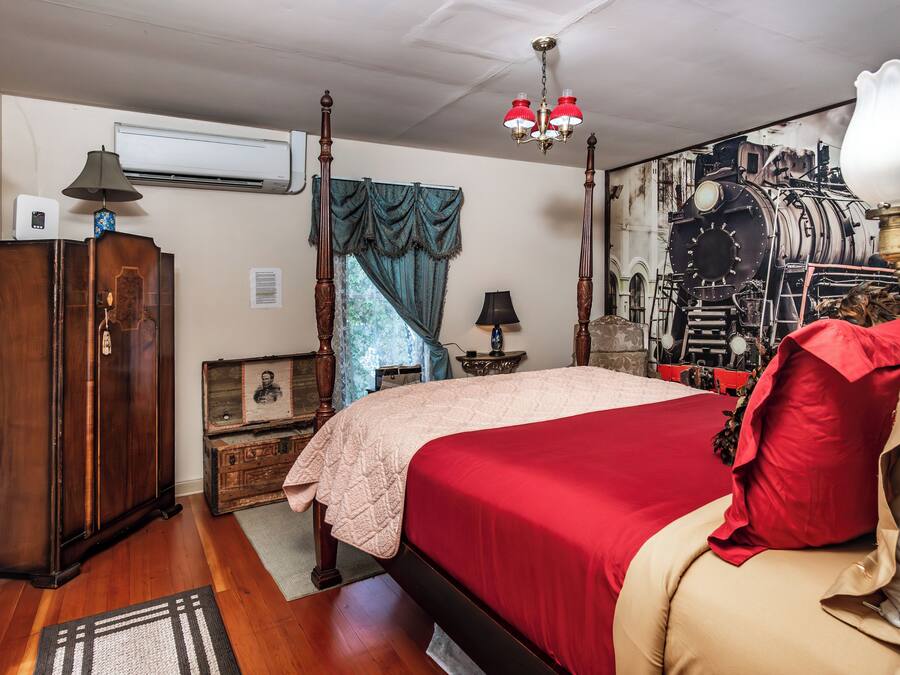 Ein Schlafzimmer mit einem großen Bett, einem Holzschrank und einer Lampe im Vintage-Stil.