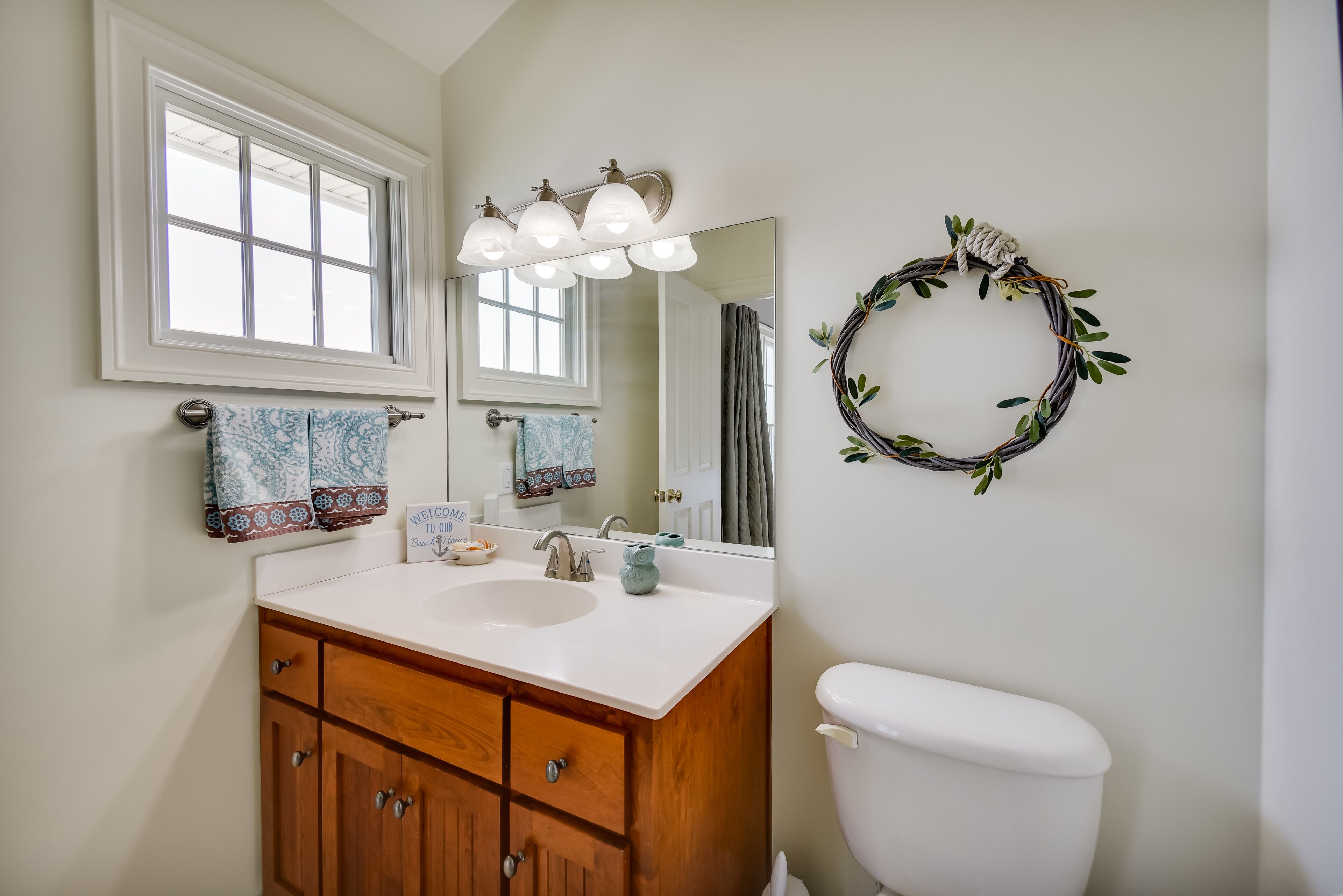 A bathroom with a white sink, wooden vanity, a mirror, and a toilet.