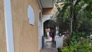 Un corridoio lastricato in pietra, con parete beige e modanature bianche, che conduce a una porta.