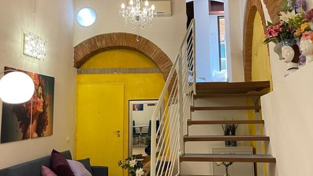 A living room with a sofa, a staircase, and a yellow door.