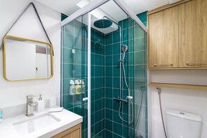 Une salle de bain moderne avec une douche à parois de verre, un lavabo blanc et des meubles en bois.