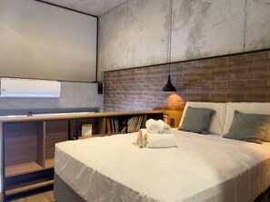 Une chambre d’hôtel moderne avec un grand lit, un bureau en bois et un mur en briques.