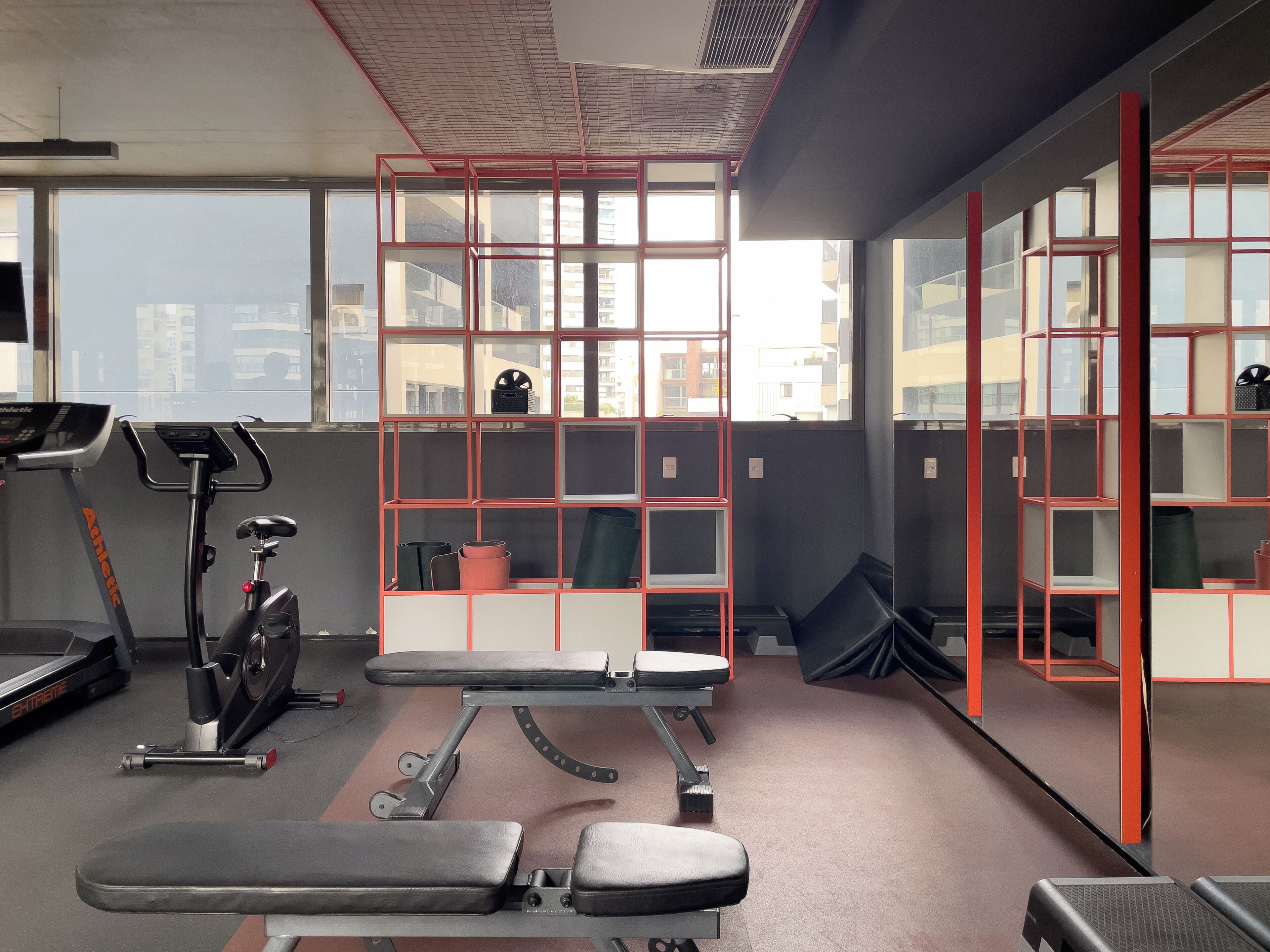 A gym with exercise equipment, a treadmill, and a bench.