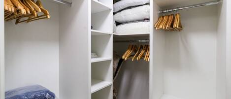 A walk-in closet with wooden hangers, shelves, and a vacuum cleaner.