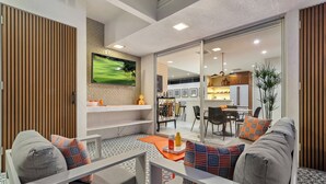 A modern living room with a sofa set, a coffee table, and a TV mounted on the wall. - The Desert Breeze at Sandpiper; Completely remodeled with private spa! (Palm Desert)