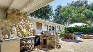 An outdoor kitchen with a stone wall, built-in grill, and wine storage. - Santa Barbara Vacation Rental w/ Pool & Hot Tub! (Santa Barbara)