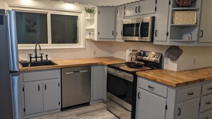 A modern kitchen with grey cabinets, a stainless steel refrigerator, a microwave, and an oven.