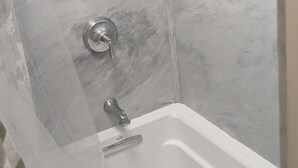 A corner shower with a built-in sink, marble walls, and a showerhead.