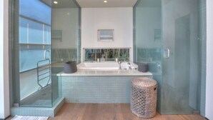 Une salle de bain moderne dotée d’une douche à parois de verre, d’une grande baignoire et d’une petite fenêtre offrant une vue agréable.
