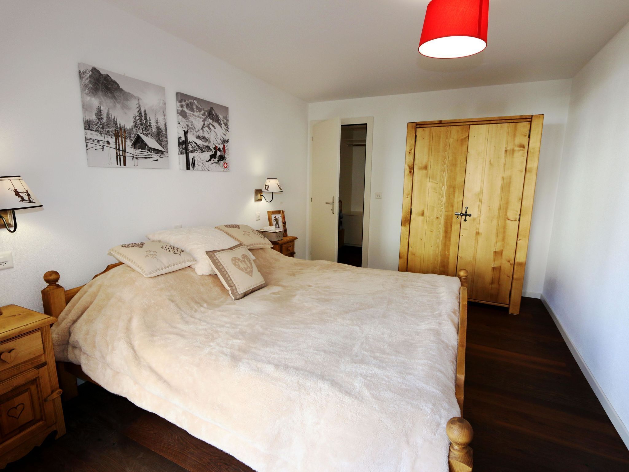 A bedroom with a wooden bed, a wooden wardrobe, and two wall-mounted picture frames.
