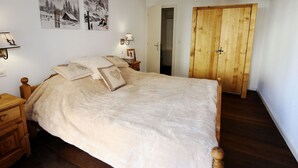 Ein Schlafzimmer mit einem hölzernen Bett, einem Schrank aus Holz und zwei an der Wand befestigten Bilderrahmen.