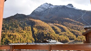 Una cabana a la muntanya amb vista a un pic cobert de neu i un bosc de colors tardans.