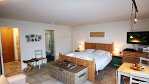 Una camera da letto con un letto di legno, una televisione, un tavolo da pranzo e un cesto in vimini.