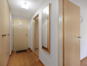 Um corredor com piso de madeira, paredes brancas e portas com molduras de madeira.