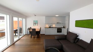 Ein modernes Wohnzimmer mit einem dunkelgrauen Sofa und einem Essbereich mit einem Holztisch und Stühlen.