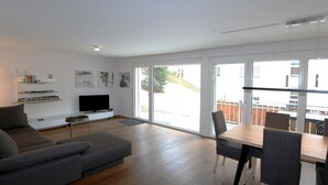 Ein modernes Wohnzimmer mit einer Couch, Fernseher und Essbereich.