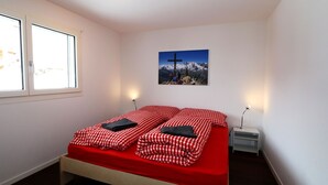 Ein Schlafzimmer mit einem Bett, zwei Nachttischen, einem Fenster und einem Wandbild.
