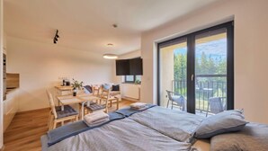 Un dormitorio moderno con una cama grande, un escritorio y un balcón con vistas a árboles.