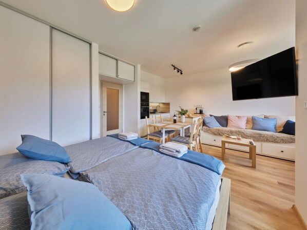 Un dormitorio moderno y bien iluminado, con dos camas, un comedor y una sala de estar.