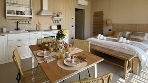 Een gezellige kamer met een houten plafond, een ontbijttafel gedekt en een bed met kussens, plus een hanglamp.