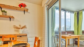 A modern dining area with a wooden table and chairs, a potted plant, and a view through a glass door. - Les Terrasses de l'Atlantique by Interhome (Lacanau)