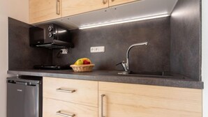 A modern kitchen with wooden cabinets, a stainless steel range hood, a built-in dishwasher, and a fruit basket on the countertop.