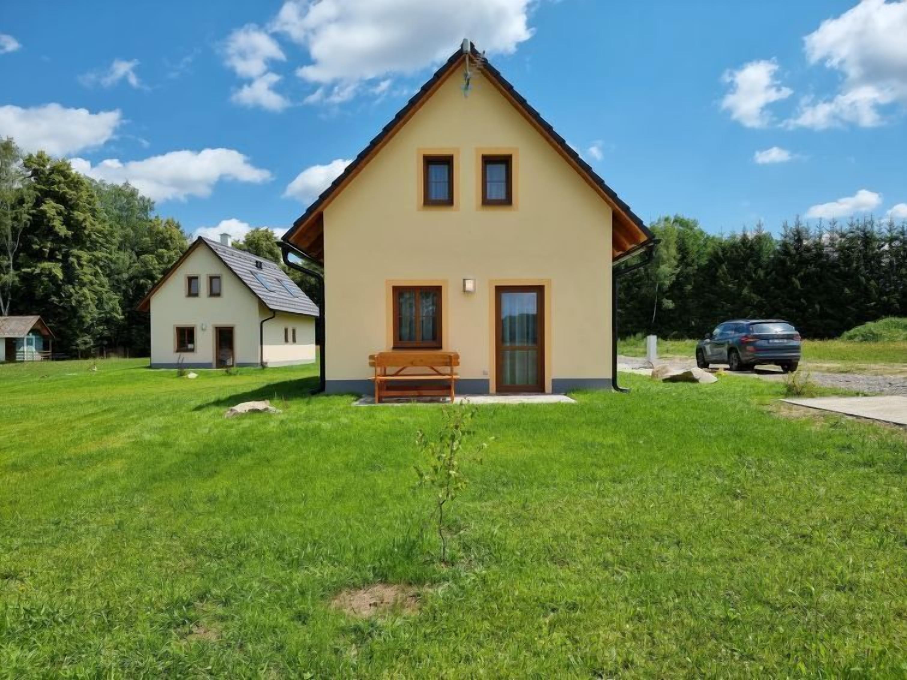 Une maison de plain-pied avec un toit en pente, un porche à l’avant et un petit banc.