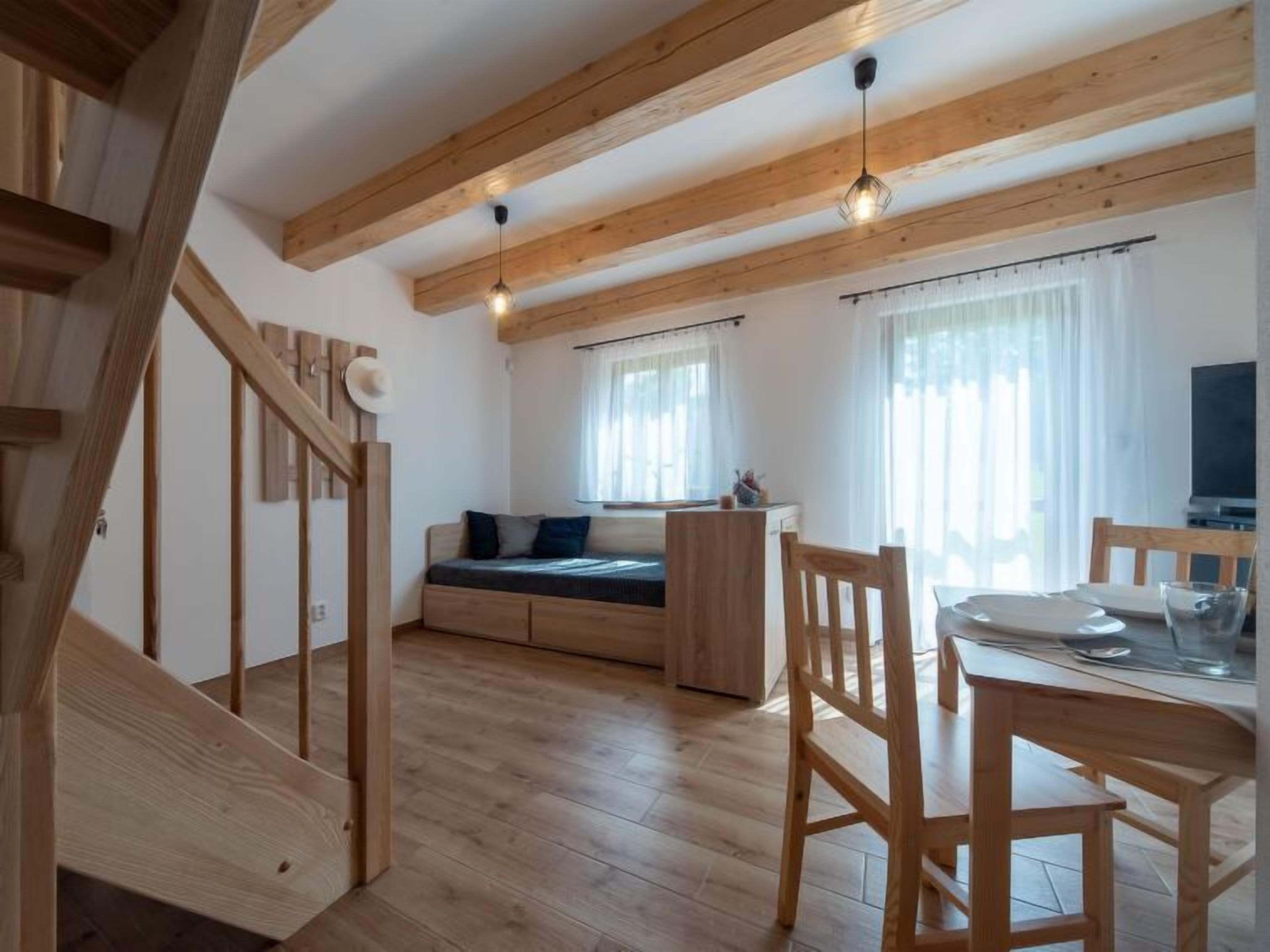 Een houten interieur met een trap, een eethoek en een zithoek met uitzicht op het landschap.