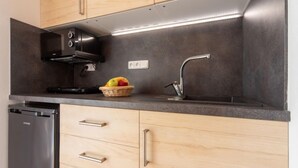 A modern kitchen with wooden cabinets, a stainless steel range hood, a built-in dishwasher, and a fruit basket on the countertop. - Vacation home Bára 1 by Interhome (Straz nad Nezarkou)