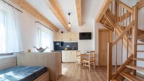 Un espacio habitable moderno y de concepto abierto, con cocina, comedor y una cama en altillo.