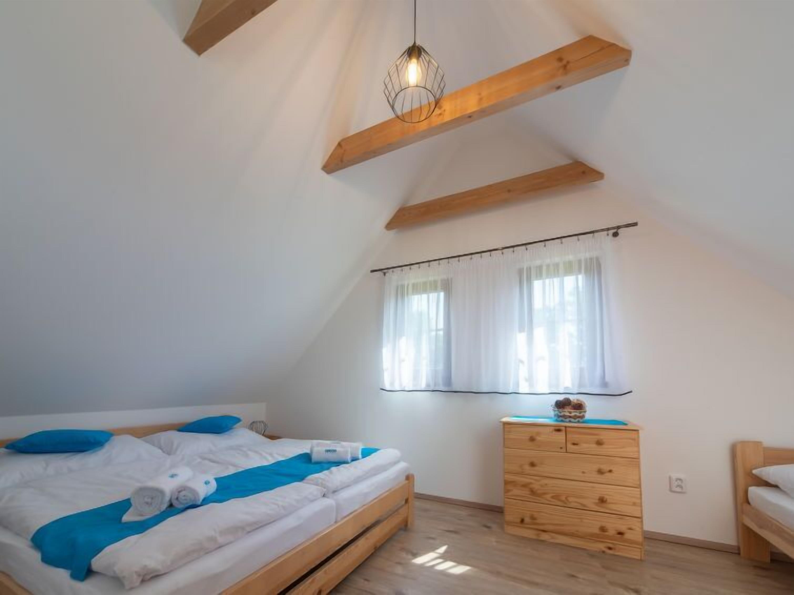 Une chambre à coucher avec un lit en bois, une commode et une fenêtre ornée de rideaux légers.