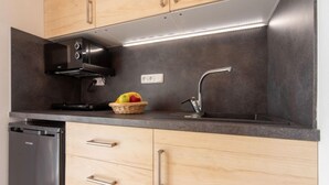 Una cocina moderna con horno empotrado, pileta de acero inoxidable y alacenas de madera.