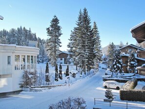A snow-covered residential area with houses, a curved building with large windows, and a clear sky.