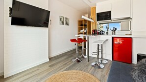A modern kitchen with a flat-screen TV, red bar stools, a red refrigerator, and a microwave. - WELCS ESTUDIO 070 EMP frente al Mar (Empuriabrava)