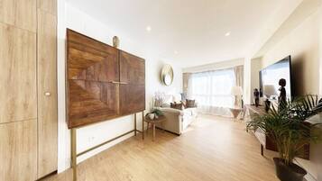 Una sala de estar moderna con un mueble grande de madera, un espejo redondo, un sofá, una mesa de centro y un televisor.