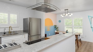 Cozinha moderna com geladeira de aço inoxidável, forno embutido e bancada de granito.