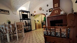 Una sala de estar acogedora con chimenea, una mesa de comedor con sillas y una cocina visible a través de un arco.