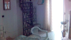 Una habitación con una escalera, una silla de plástico blanca, una pequeña mesa y una ventana con cortinas.